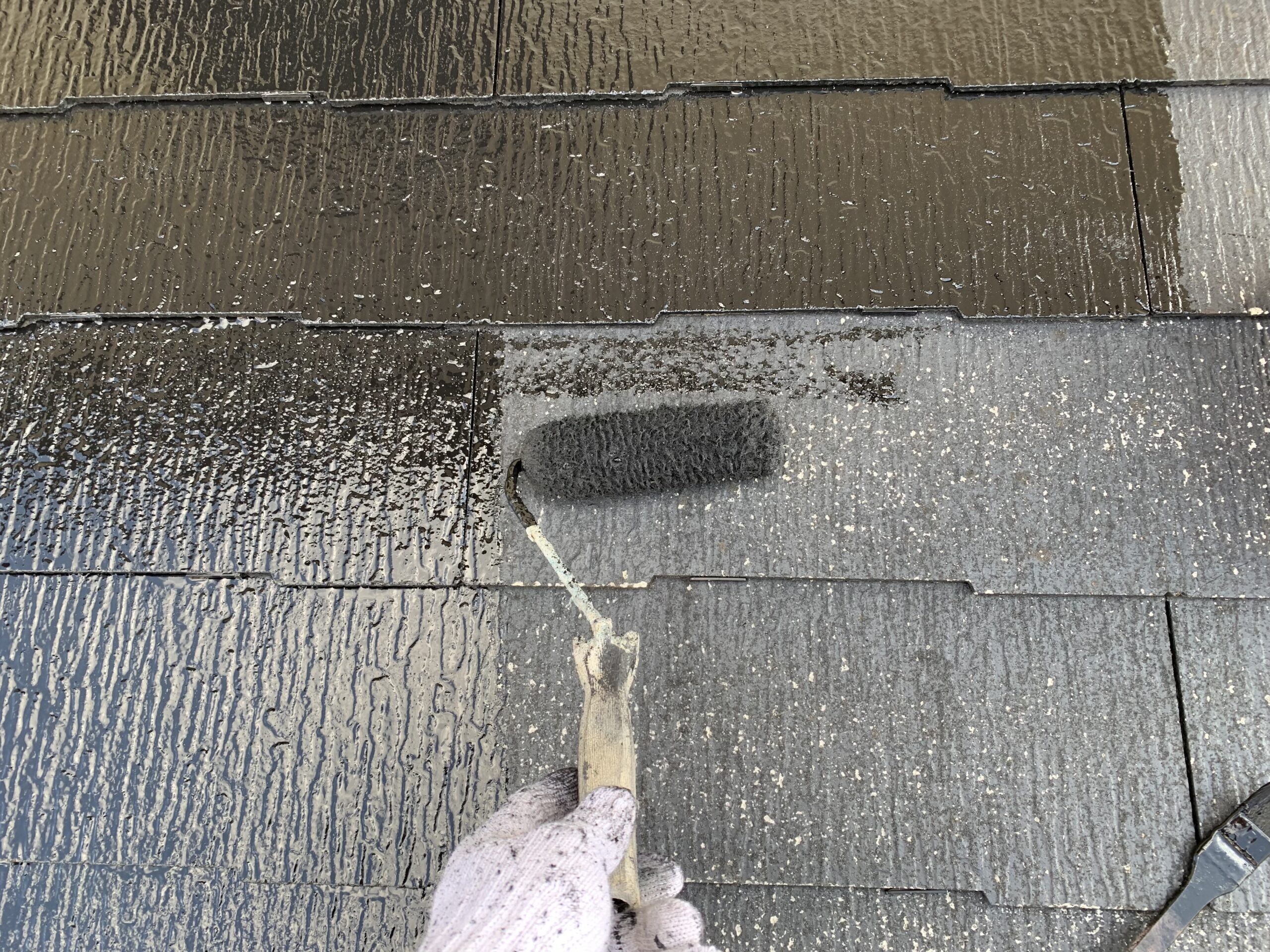 屋根の上塗り１回目を塗っている写真