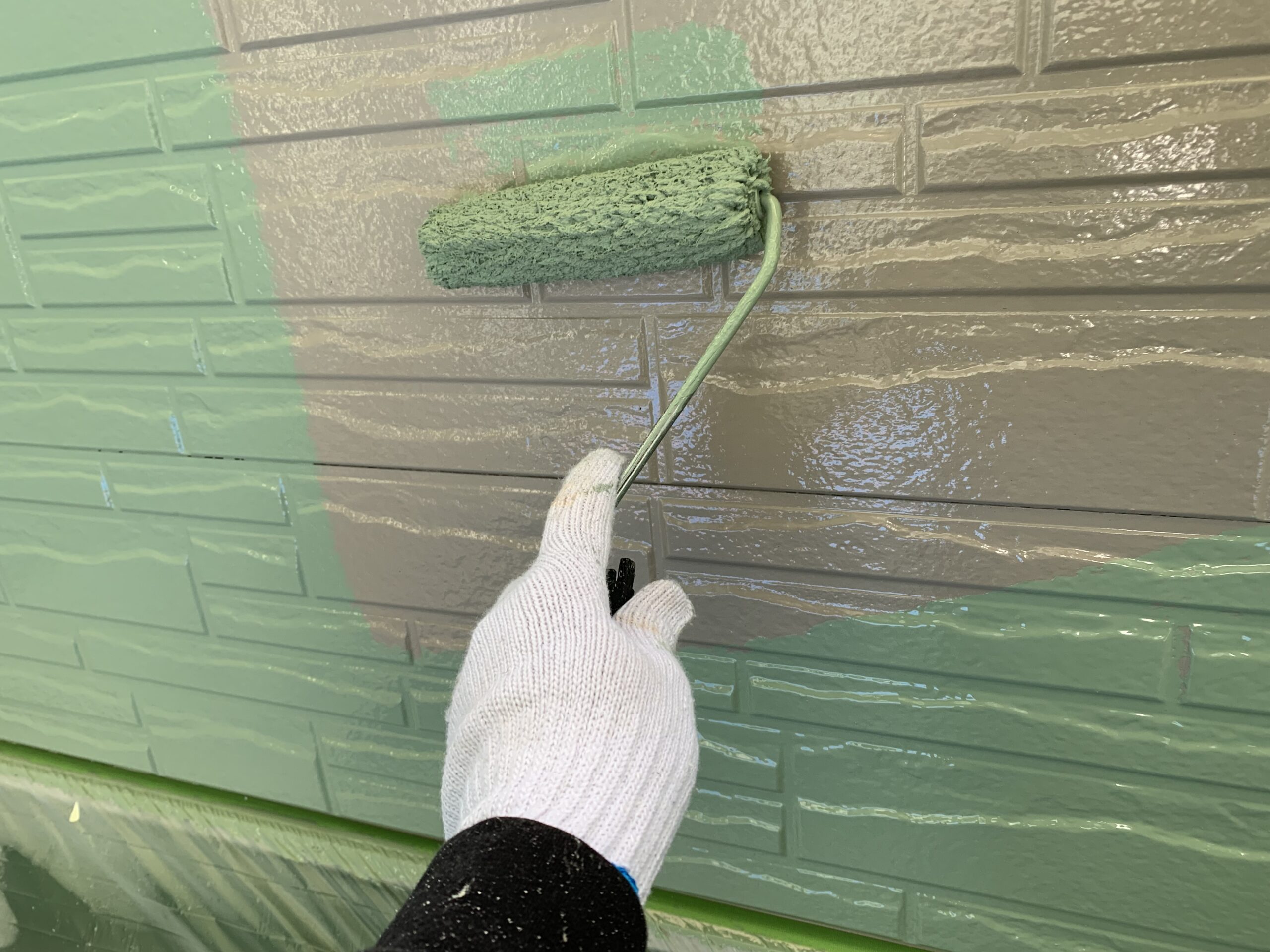 外壁の上塗り１回目を塗っている写真