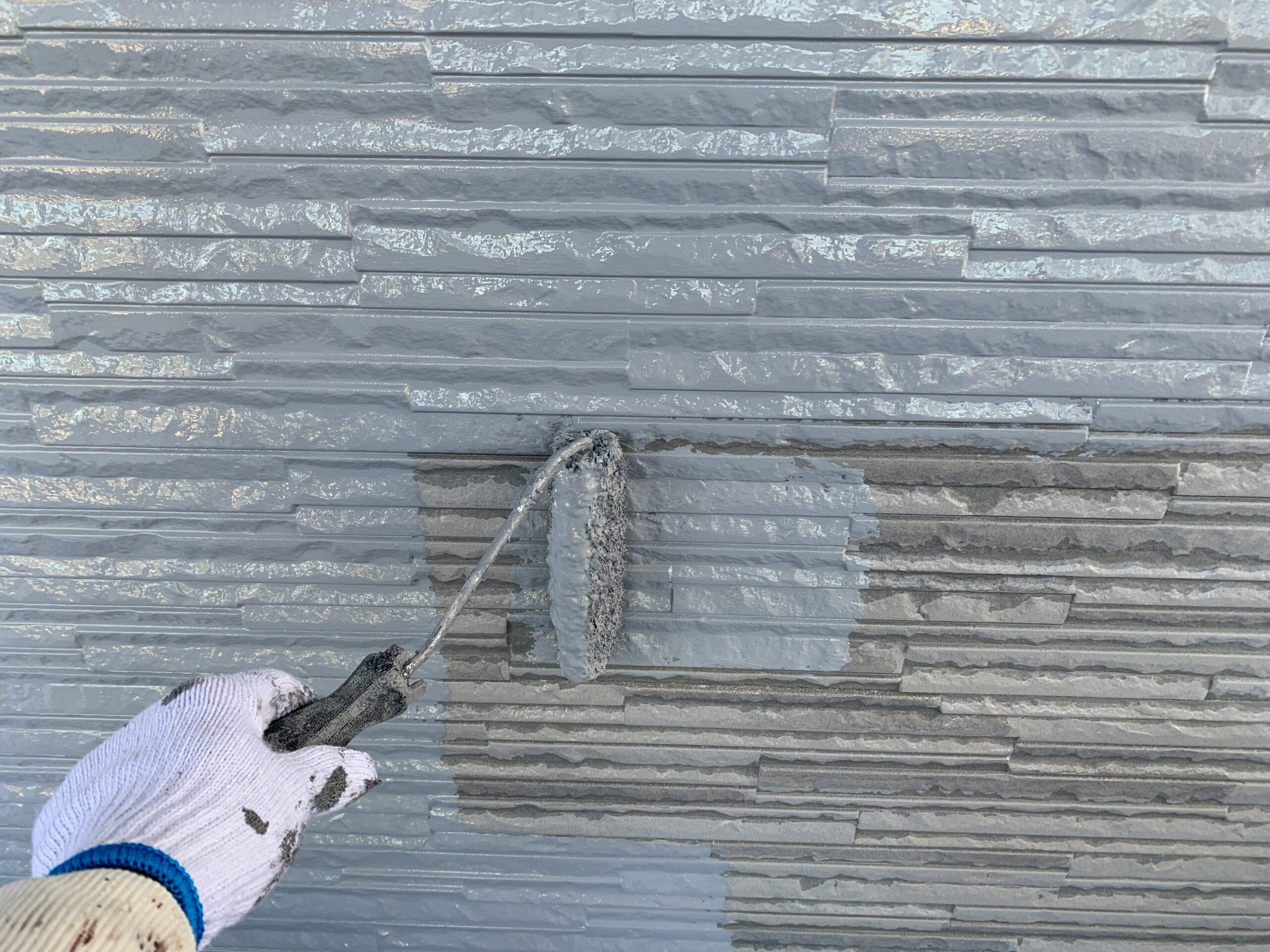 外壁の上塗り１回目を塗っている写真
