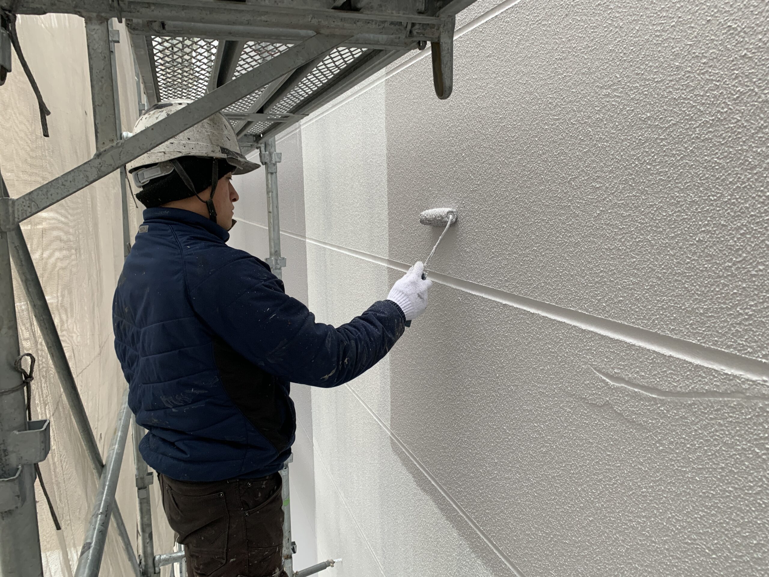 外壁の上塗り１回目を塗っている写真